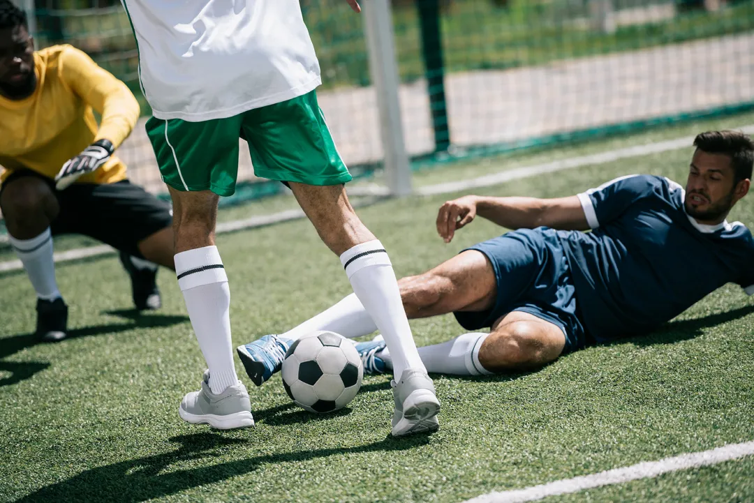 multiethnic soccer players playing soccer on pitch together Soccer Players